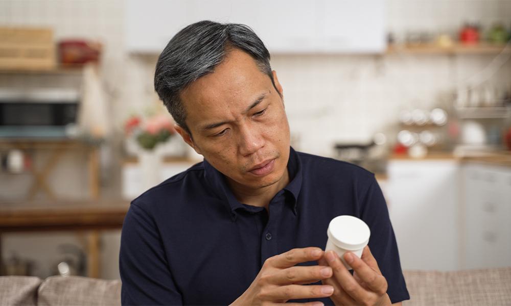 man looking at pill bottle
